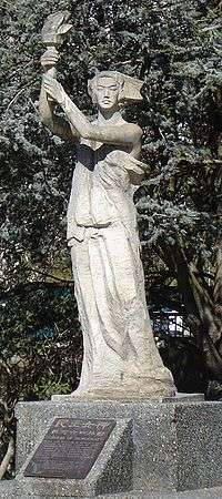 A defiant woman in a robe holding aloft a torch