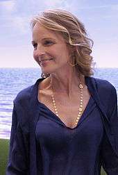 Upper torso of a blonde haired lady wearing a navy blue dress and shawl.
