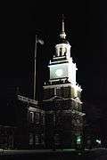 alt=The clock tower of a large brick building at night