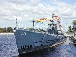 alt=A submarine tied to a dock, flying many signal flags.